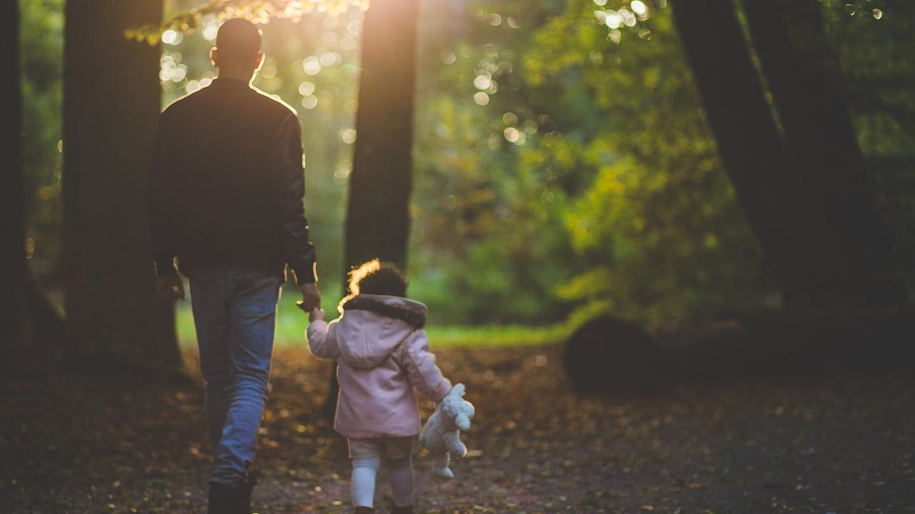 A Man and a Little Girl Walking in the Forest Area